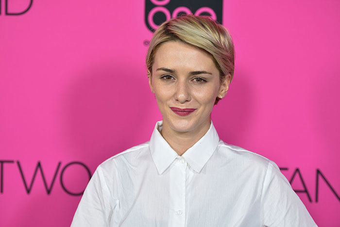 Addison Timlin from the cast of High Potential in front of a pink background, wearing a white shirt.