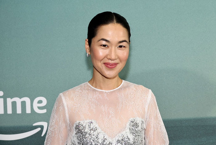 Jackie Chung from The Summer I Turned Pretty in a sheer white top with a subtle smile at a media event.