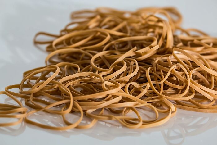 A pile of elastic rubber bands on a white surface, symbolizing clever tips for living cheap.