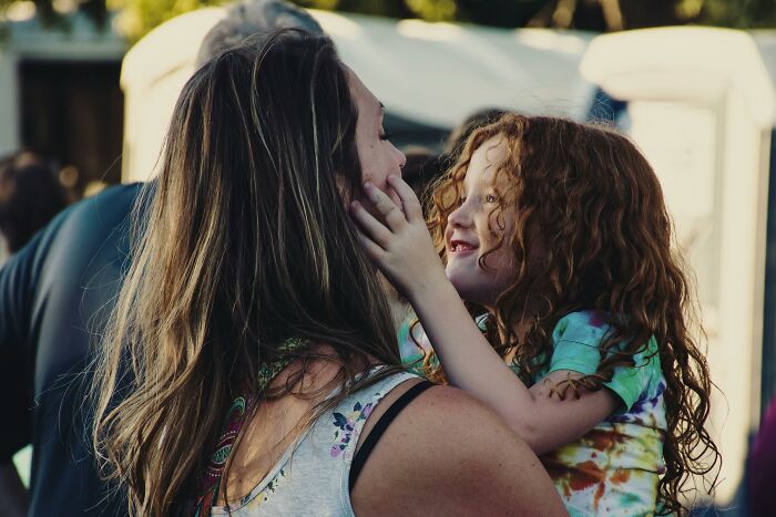 Woman holding smiling child outdoors, demonstrating clever tips for living cheap and comfortable.