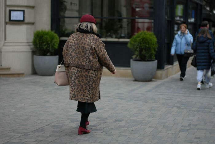 Person in a leopard coat walking on a city street, showcasing tips for living cheap yet stylishly.