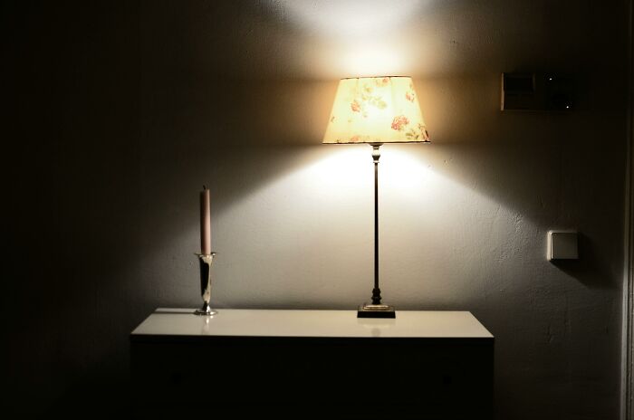 Lamp on a dresser with a candle, showcasing clever tips for living cheap while maintaining comfort.