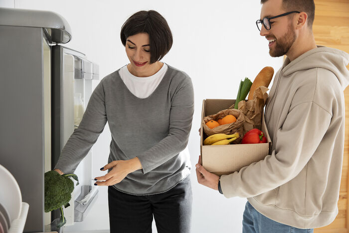 Two people organizing groceries, demonstrating clever tips for living cheap and comfortably at home.