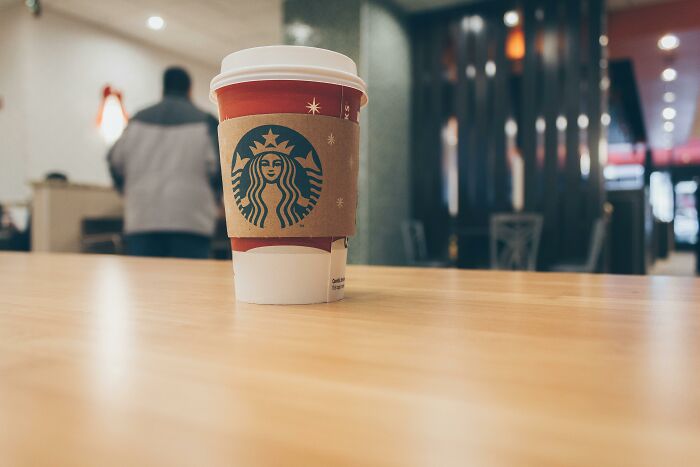 Takeaway coffee cup on a table in a cozy café setting, illustrating tips for living cheap without sacrificing comfort.