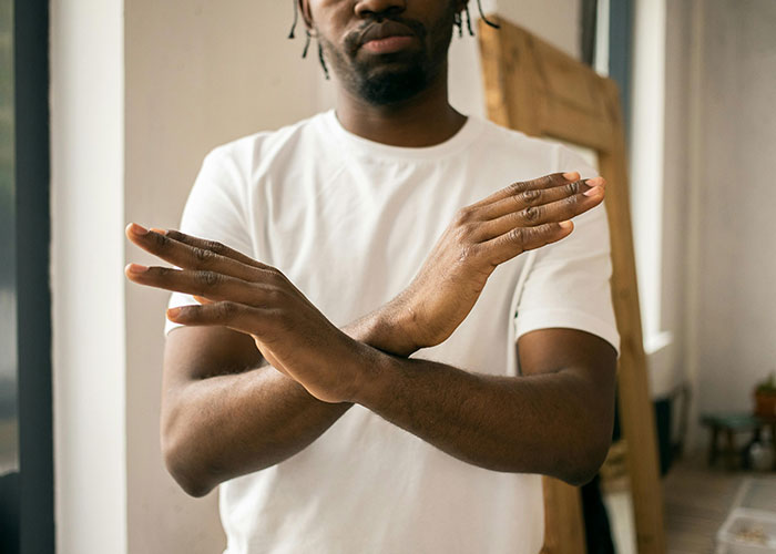 Person in a white shirt crossing arms, symbolizing "cheat codes" for life in a casual indoor setting.