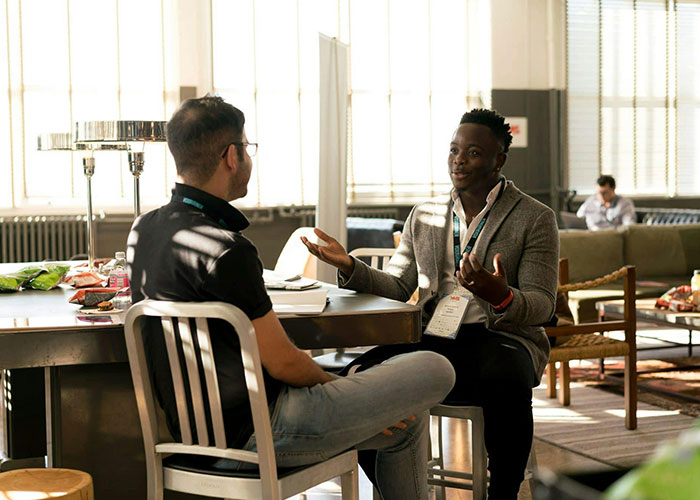 Two people having a discussion in a sunlit room, sharing life cheat codes at a casual gathering.