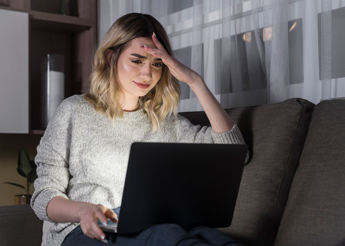 Woman on couch using a laptop, engaging in relaxed evening activities.