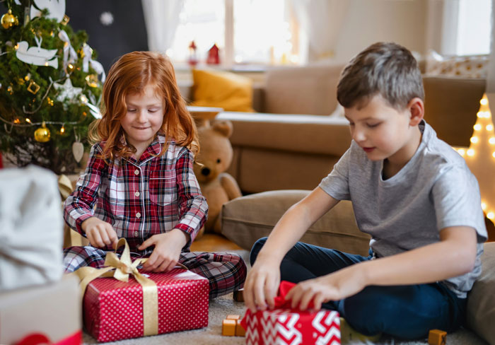 Two children opening Christmas gifts near a tree, representing the joy of finding gifts from the past.