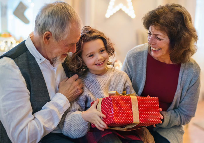 Child holds gift during home reconstruction, sharing joy with grandparents.