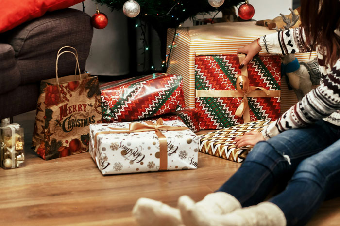 Person in festive attire discovers a wrapped Christmas gift with their name during home renovation.