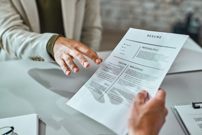 Two people exchanging a resume document across a table, focusing on resume red flags.