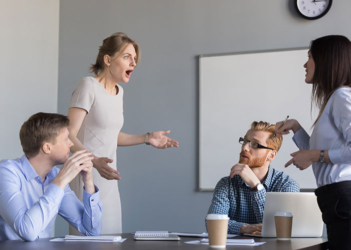 Office employees discussing at a potluck meeting, showing disappointment.