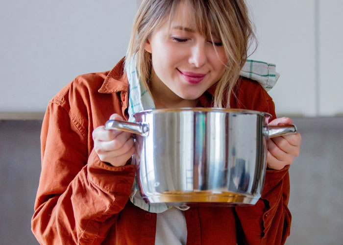 Person in a kitchen holding a pot, possibly representing company potluck disappointment.