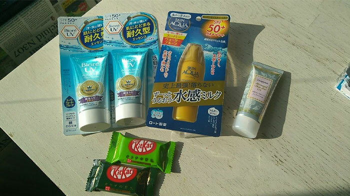 Cool products with surprises, featuring sunscreen lotions and Japanese KitKats on a wooden surface.