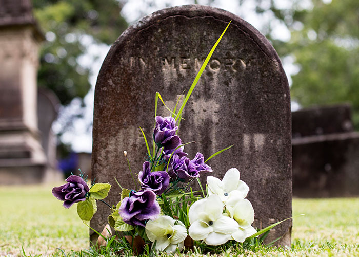 Tombstone with flowers, symbolizing unspoken family secrets buried in memory.