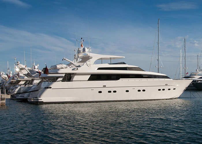 A luxury yacht docked at a marina under a clear blue sky.