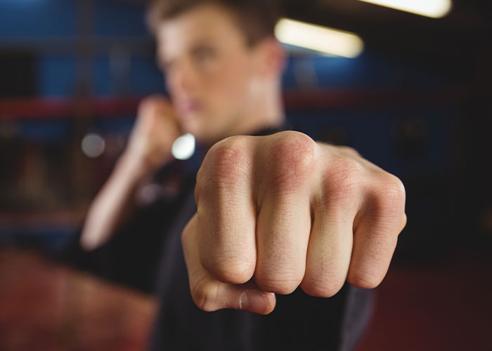 A man in a fighting stance with a focus on his fist, symbolizing hidden family secrets.