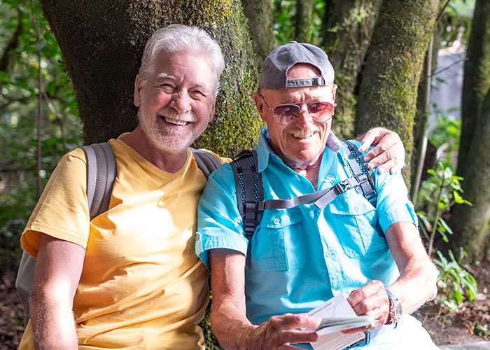 Two older men smiling together outdoors, one wearing a yellow shirt, symbolizing untold family secrets.