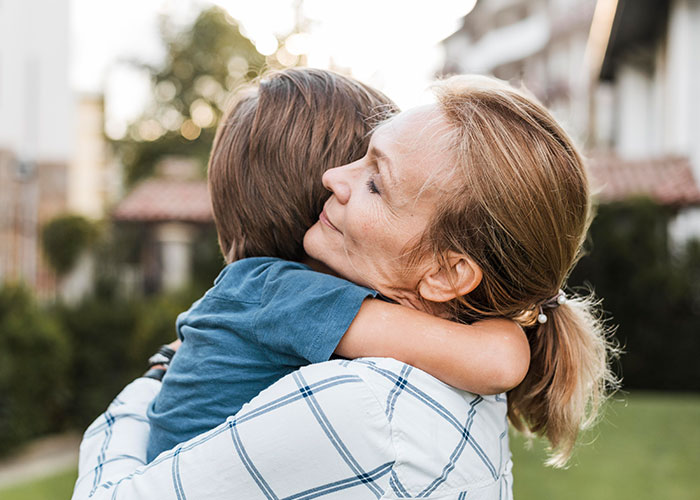 A woman hugging a child in a garden, expressing warmth and secrecy.