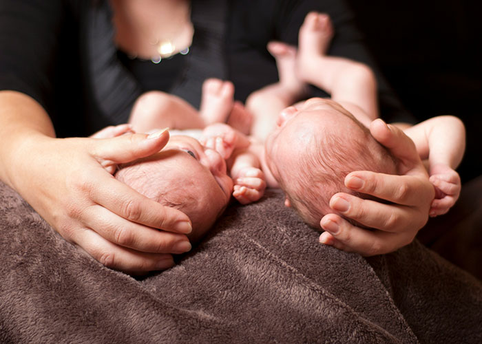 Hands holding newborn babies against a dark background, related to unsettling medical facts.