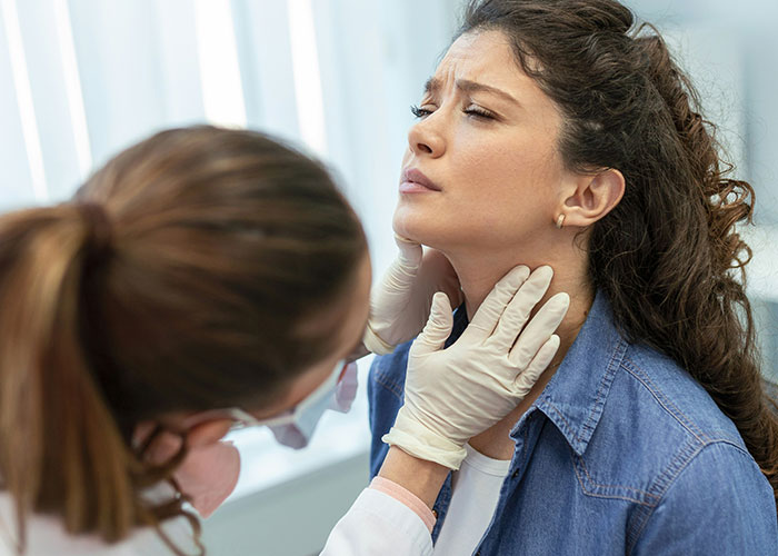 Doctor examining woman's throat; unsettling medical assessment.