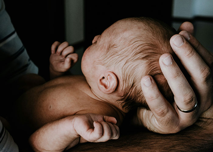 Newborn baby cradled in a hand, illustrating medical facts and natural beginnings.