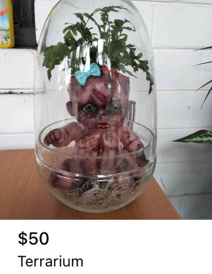 Creepy doll terrarium with plant, available for sale online for $50.