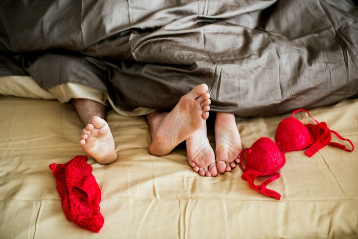 Feet under covers with red lingerie on bed, illustrating untold family stories.