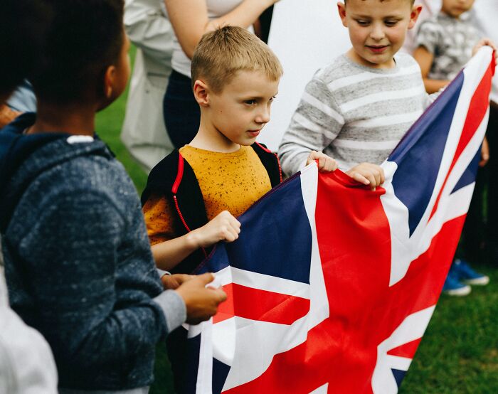 Children holding a British flag, symbolizing kids feeling like foreigners in a different country.