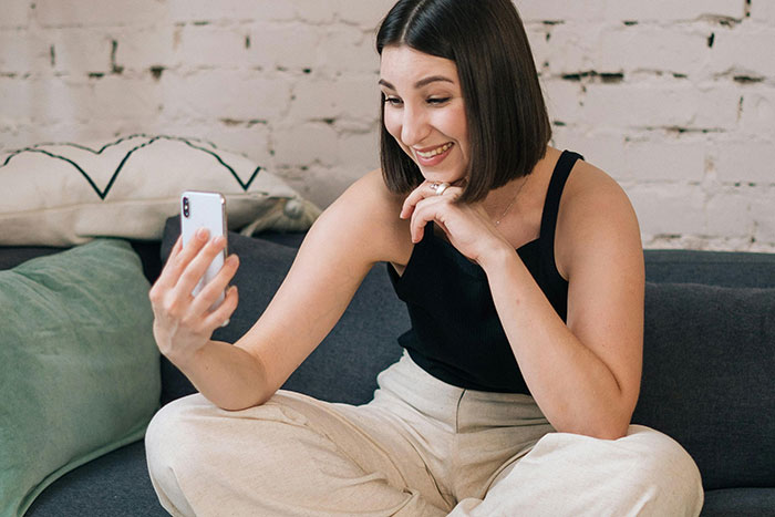 Person smiling while video chatting on a couch, showcasing adorable moments with their partner.