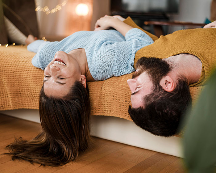 Couple sharing a joyful moment, lying on a bed, showcasing adorable partner interactions.