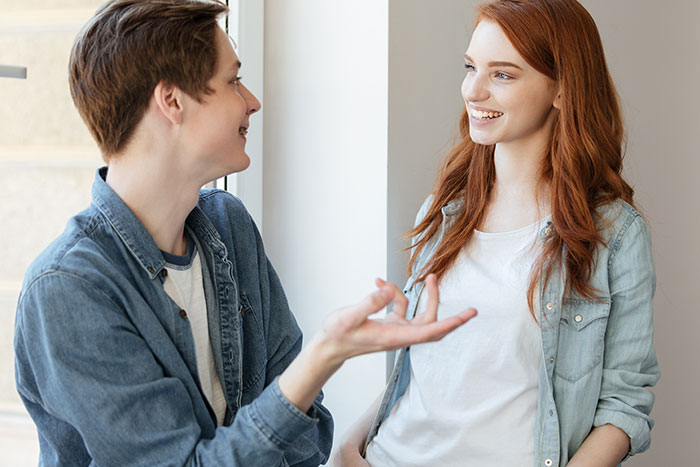 Couple smiling and talking by a window, capturing adorable moments with partners.