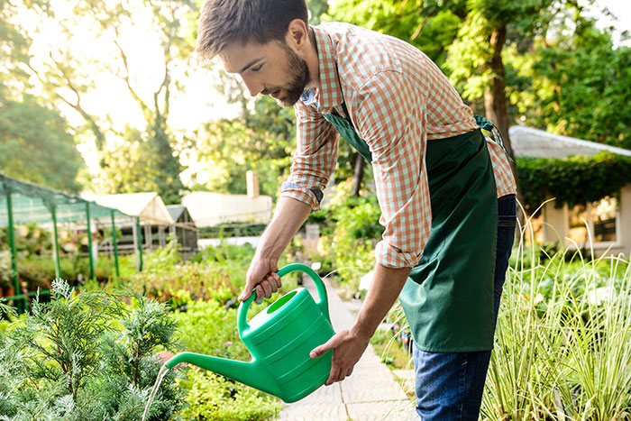 A man in an apron watering plants in a garden, showcasing an adorable act of care that defines "my person".