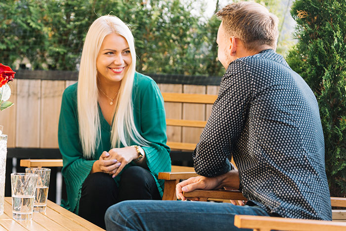 Couple sitting outside, smiling and conversing, showcasing adorable partner interactions.