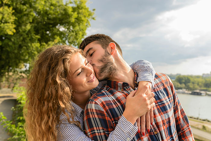 Couple embracing outdoors, showing affection and happiness, capturing adorable moments that make partners feel cherished.