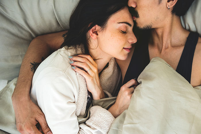 Partners cuddling in bed, creating an adorable moment of affection and closeness.