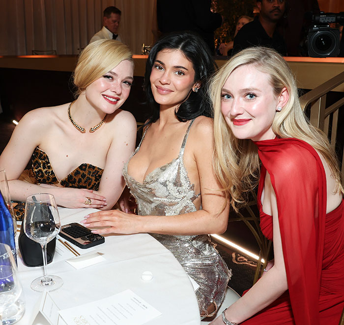 Three women in elegant dresses at an event, with one wearing a vintage silver dress.