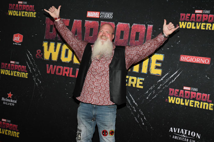 Randal Reeder in a patterned shirt and jeans at Deadpool and Wolverine premiere event backdrop.