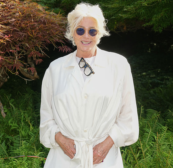 Deborra-Lee Furness smiling outdoors in a white outfit, wearing sunglasses.