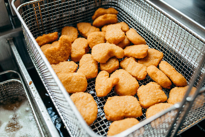 Chicken nuggets in a fryer basket, illustrating a revengeful job exit scenario in the food industry.