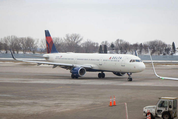 Delta airplane on a snowy tarmac, highlighting airline's role in urgent travel assistance.