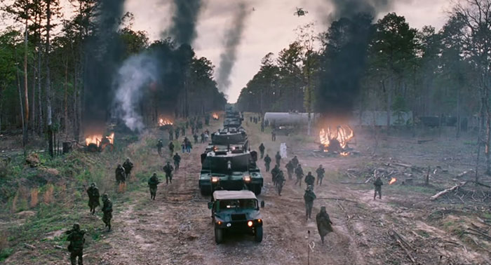 Military convoy in a forest with smoke and fire, depicting a sad and depressing movie ending.