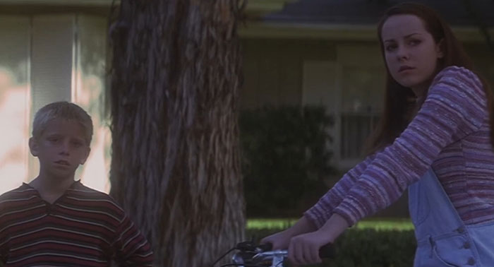 Two children stand with somber expressions, reflecting on a sad movie ending.