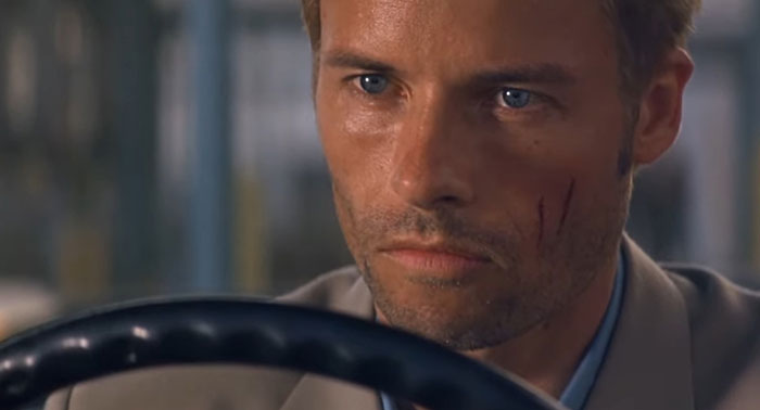 Man with scratched face in a car, representing a sad movie ending.