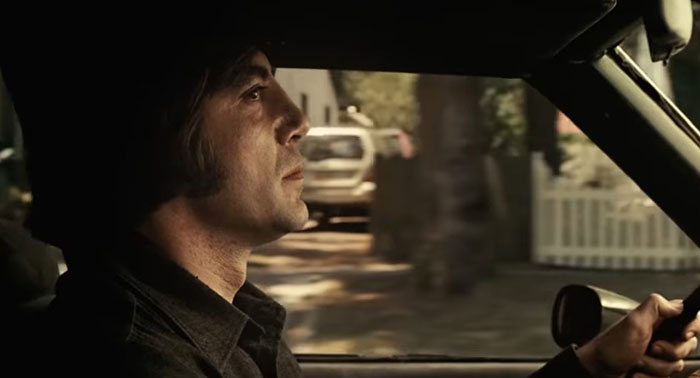 A man driving a car in a scene with a sad movie ending, intense expression on his face.