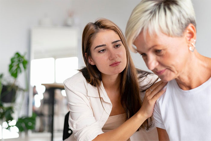 Young woman comforts an older woman, expressing concern about walking down the aisle.