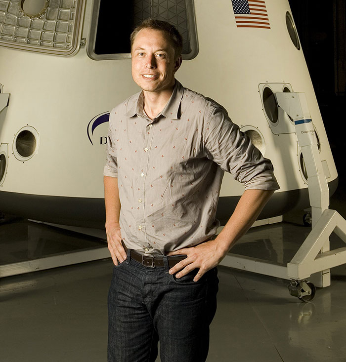 Man in casual attire standing in front of a spacecraft, representing a wealthy entrepreneur.