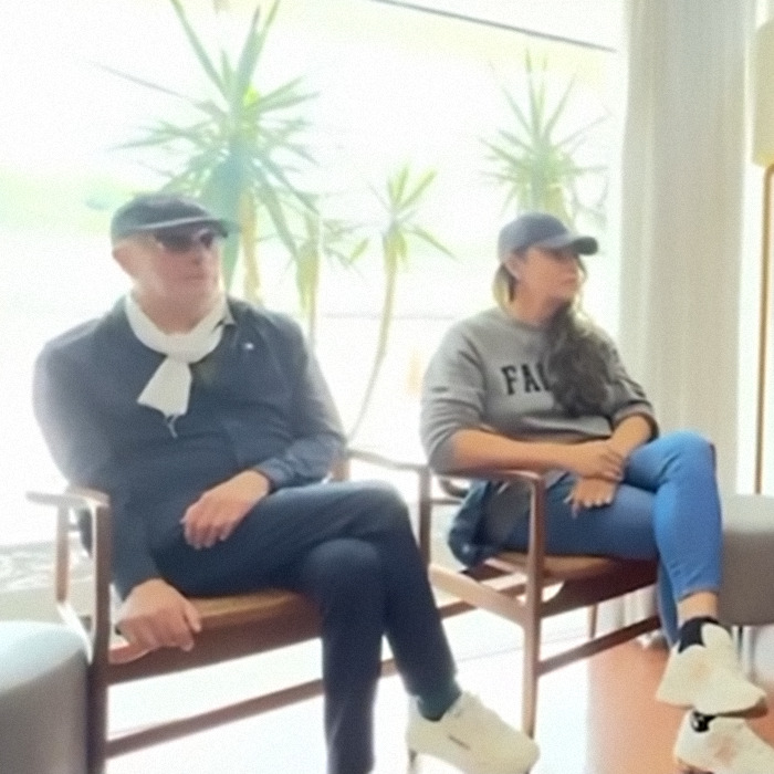 Two people seated indoors, one wearing a cap and scarf, another in a sweatshirt with "FAKE," discussing Cynthia Erivo's Oscar nomination.