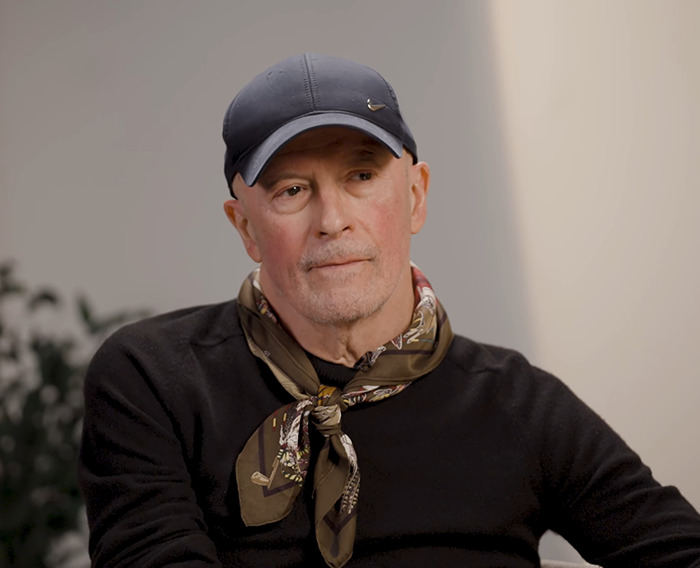 Director of 'Emilia Pérez' shaking his head, wearing a cap and a scarf, with a plant in the background.