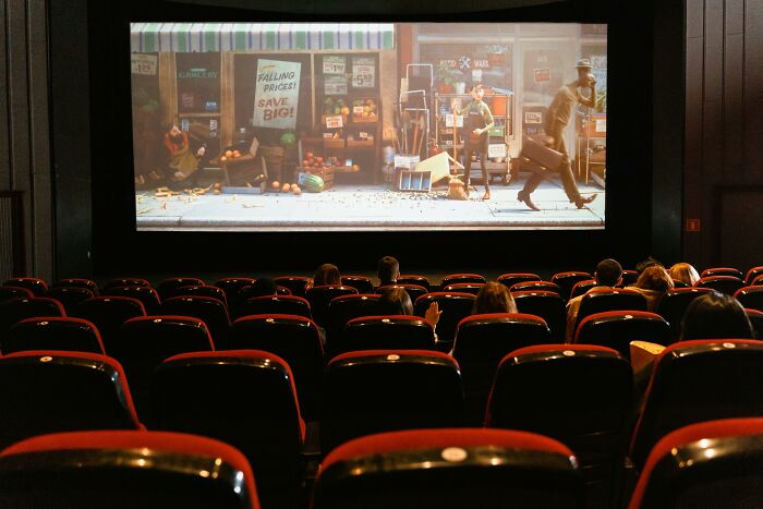 Empty movie theater showing a film, highlighting reduced attendance due to cost.